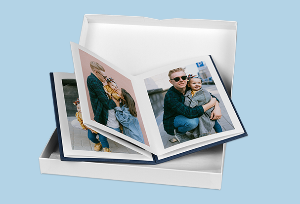 Ein geöffnetes myLeporello Buch mit Vater-Kind-Fotos inkl. einer weißen Geschenkbox, ideal als personalisiertes Babygeschenk.