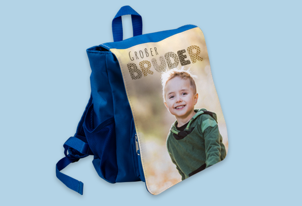 Ein blauer Kinderrucksack mit individuell bedruckter Vorderseite, die ein fröhliches Kind und den Text „Großer Bruder“ zeigt – ein kreatives und praktisches Babygeschenk zur Geburt